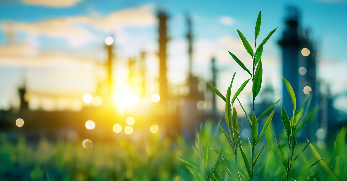 Green grasses near an industrial plant